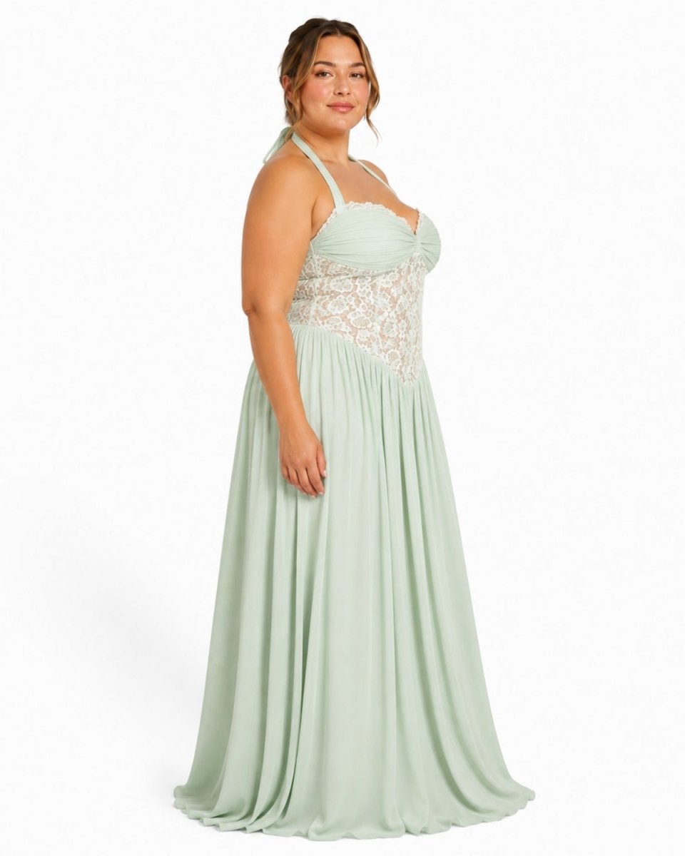 A woman modeling a floor-length mint green halter gown with a lace bodice, photographed against a plain white studio background.