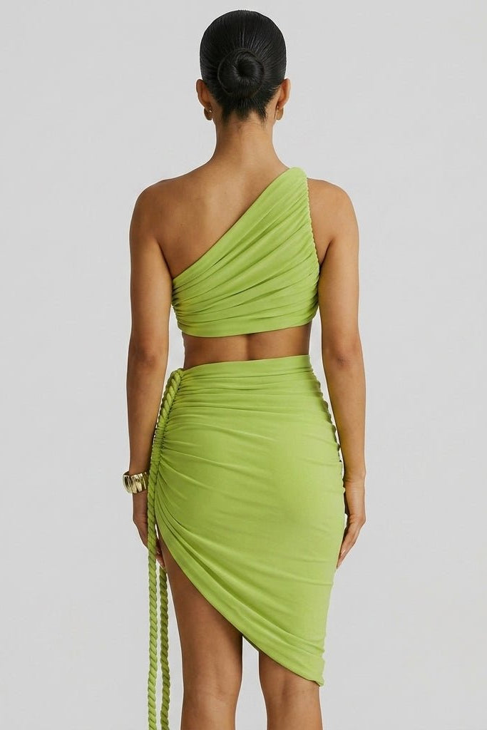 Back view of woman in Fenlo Form green bodycon dress showing asymmetric ruching and braided rope detailin