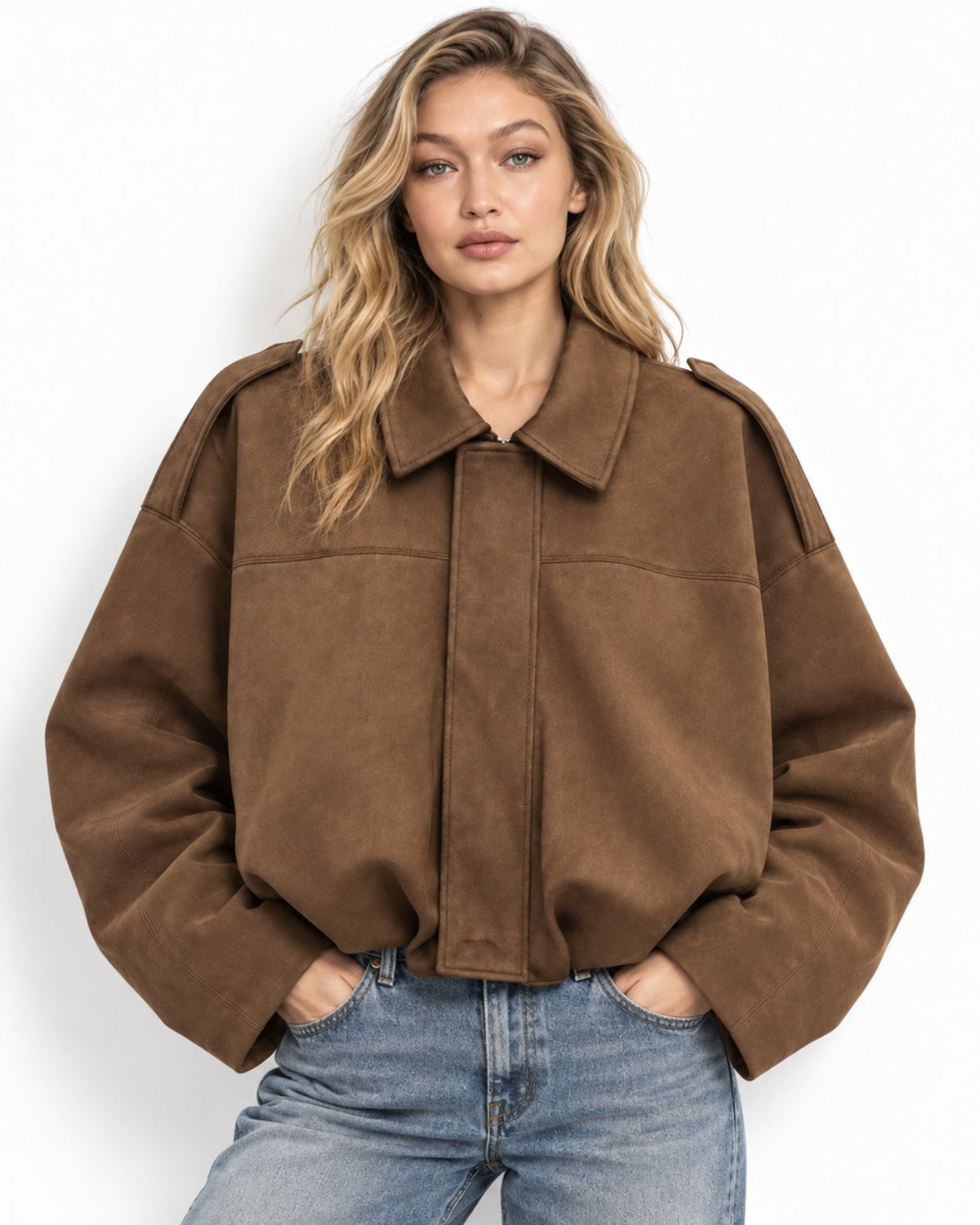A woman wearing a brown cropped suede jacket with a wide collar and front flap, paired with blue jeans, photographed against a plain white background.