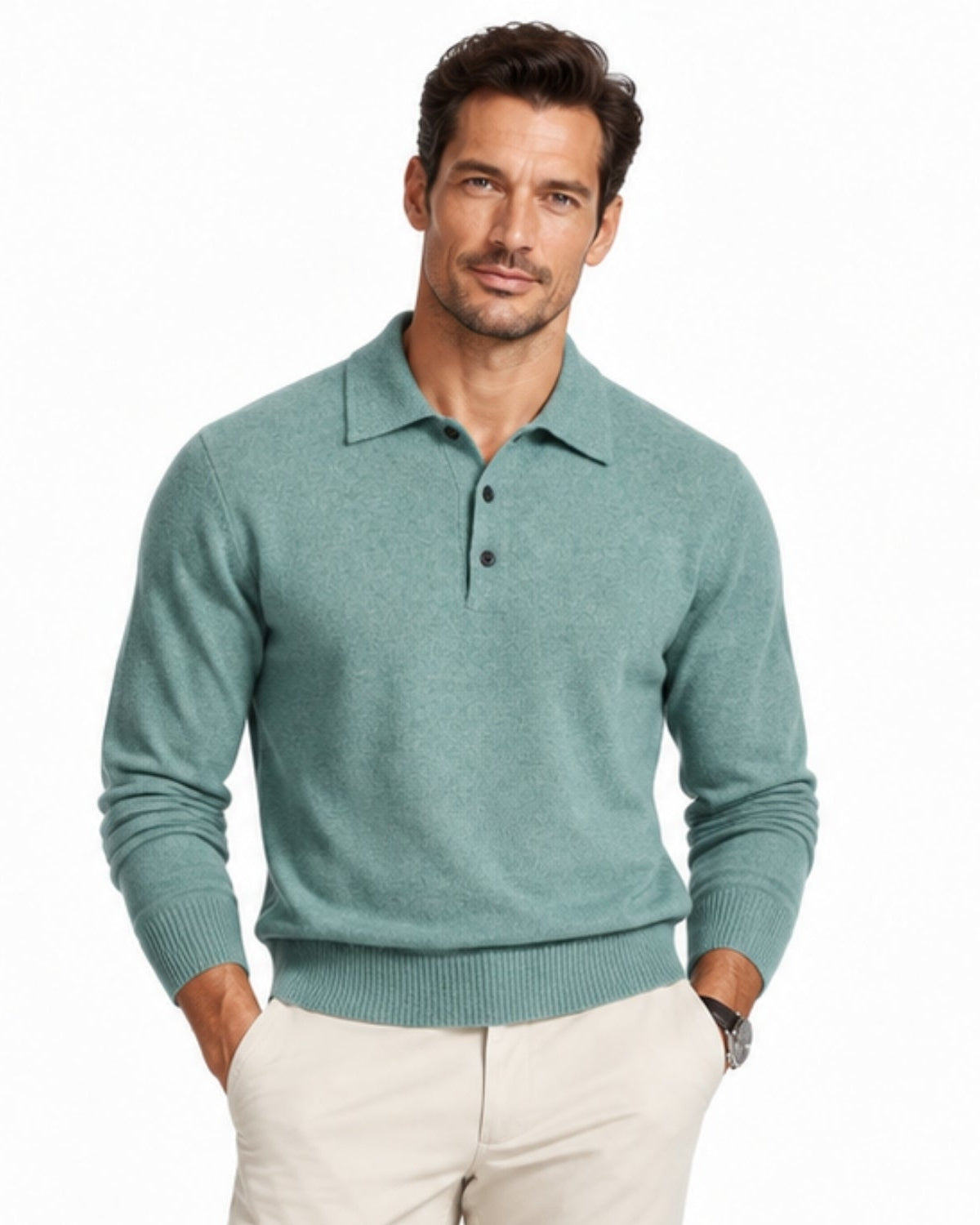 A man wearing a sage green knit polo sweater and light beige trousers, standing against a plain white background.