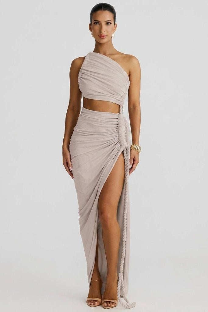 Front view of model wearing a grey one shoulder ruched cutout maxi dress with high slit and braided rope detail.