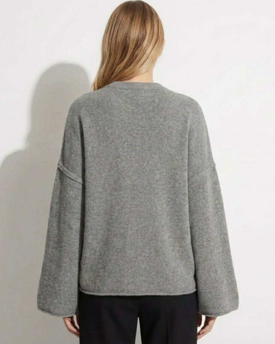 Back view of the oversized grey knit sweater, showing the minimalist silhouette and drape.