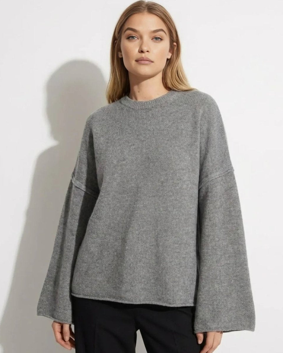 Model wearing the grey oversized bell sleeve sweater made from a cashmere and merino wool blend.