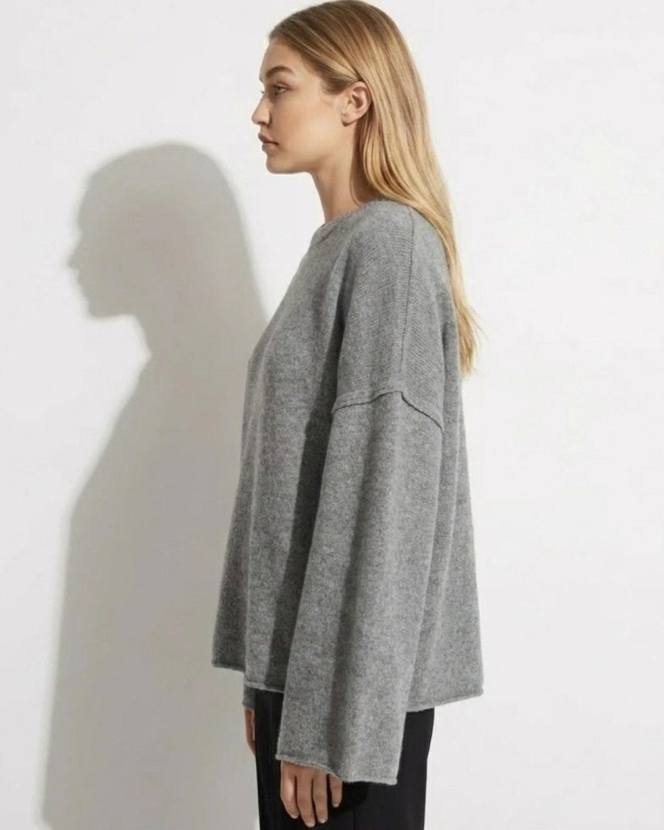 Side profile view of the relaxed fit and wide bell sleeves on the grey cashmere crewneck sweater