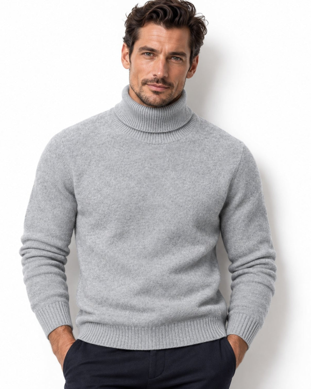 Front view of a man wearing a light grey Kouvr luxury turtleneck sweater with ribbed cuffs and a tailored fit.