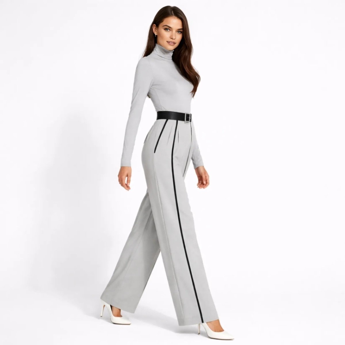 Side profile view of female model walking in the Kouvr grey tailored wide leg belted jumpsuit showcasing the flowing pant legs and tailored silhouette.