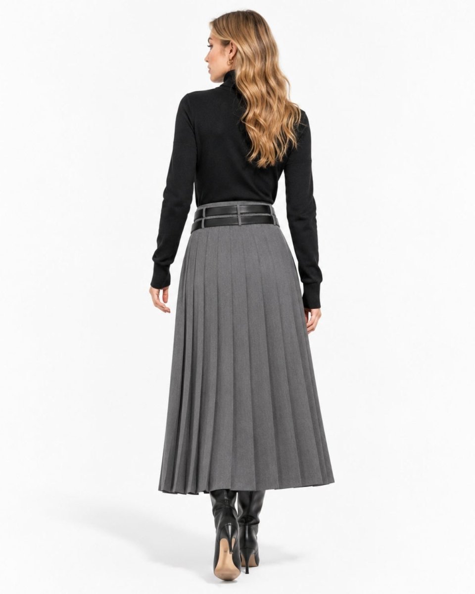 A woman shown from the back wearing a black long-sleeve turtleneck sweater, a high-waisted gray pleated skirt with a black belt, and black ankle boots, against a plain white studio background.