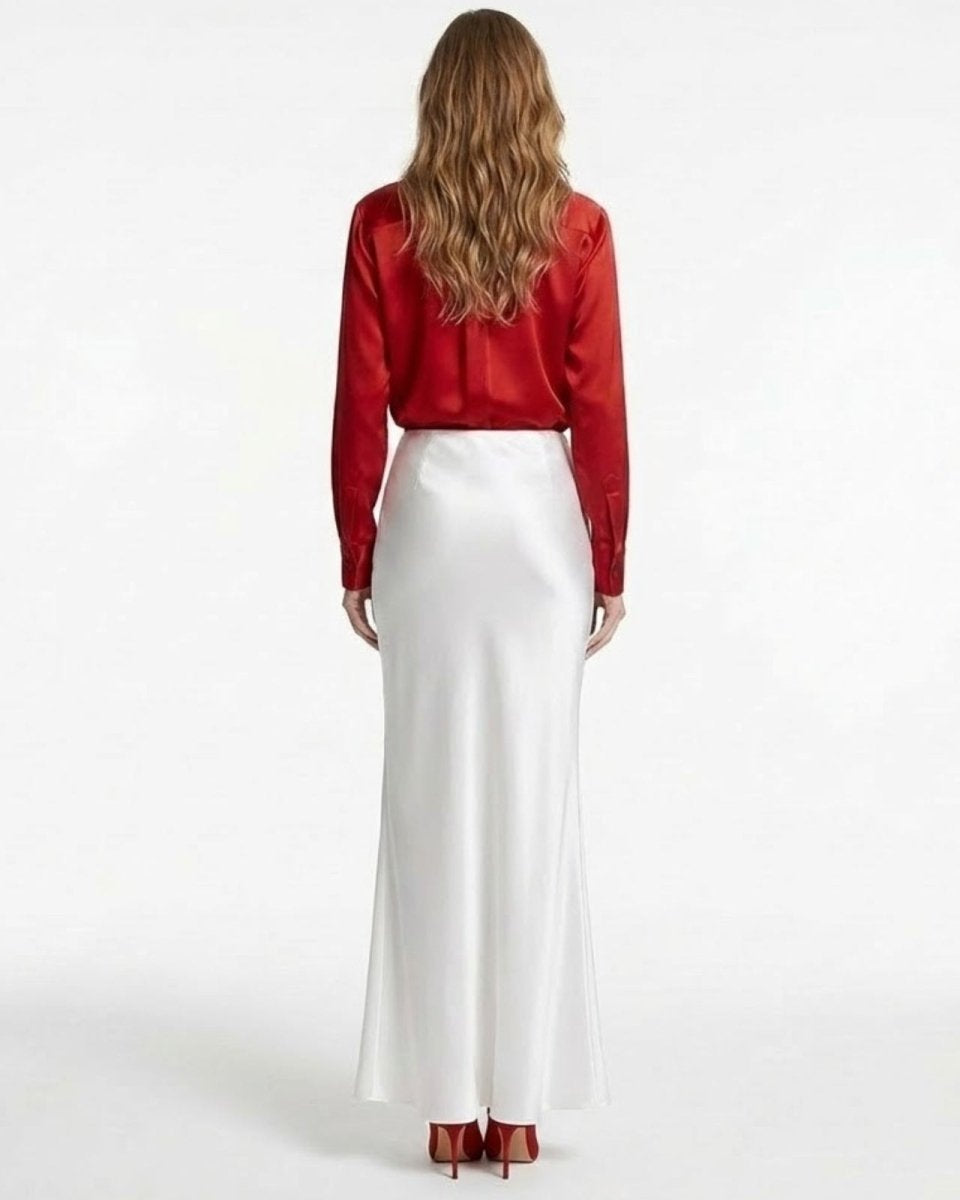 Back view of a woman in a high-waisted white silk maxi skirt from, showcasing its clean lines and luxurious sheen.
