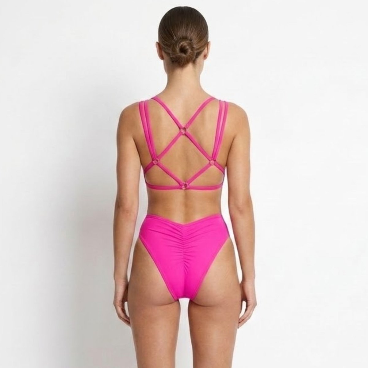 Detailed back view of the hot pink swimwear showing the supportive cage back design and flattering ruched cheeky cut.