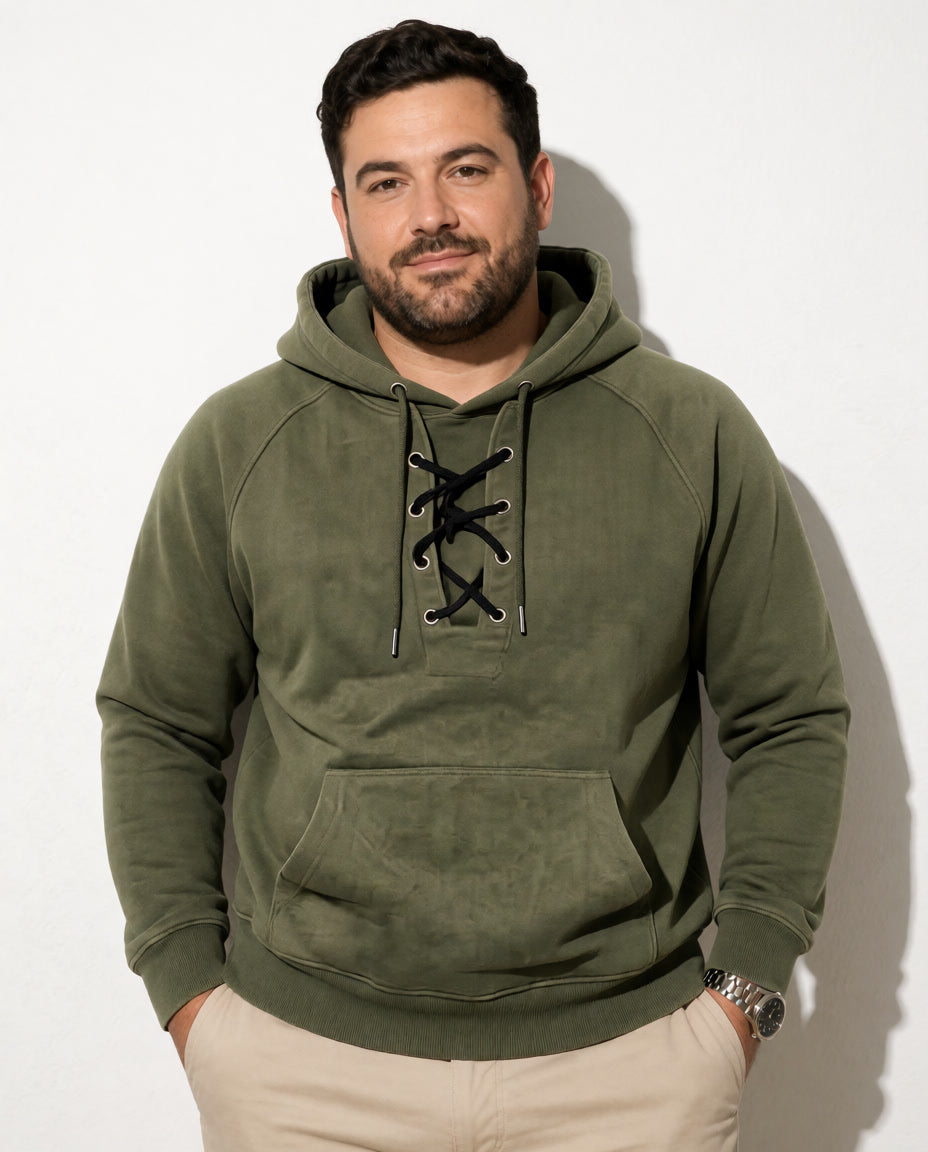 Ein Model trägt den olivgrünen Cannon Kapuzenpullover mit Schnürung zu einer hellen Hose.
