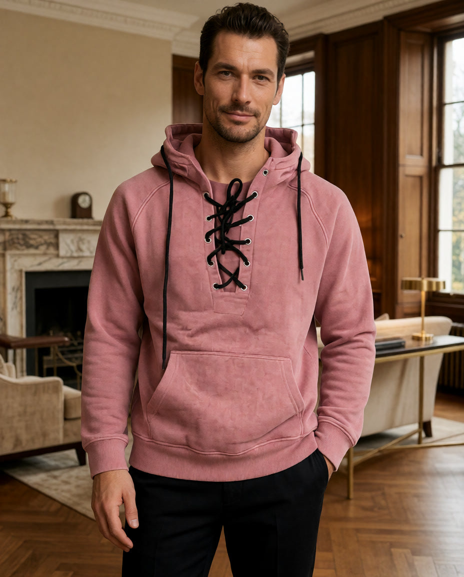 Ein Model trägt den rosafarbenen Cannon Kapuzenpullover in einem Raum mit Kamin und Holztäfelung.