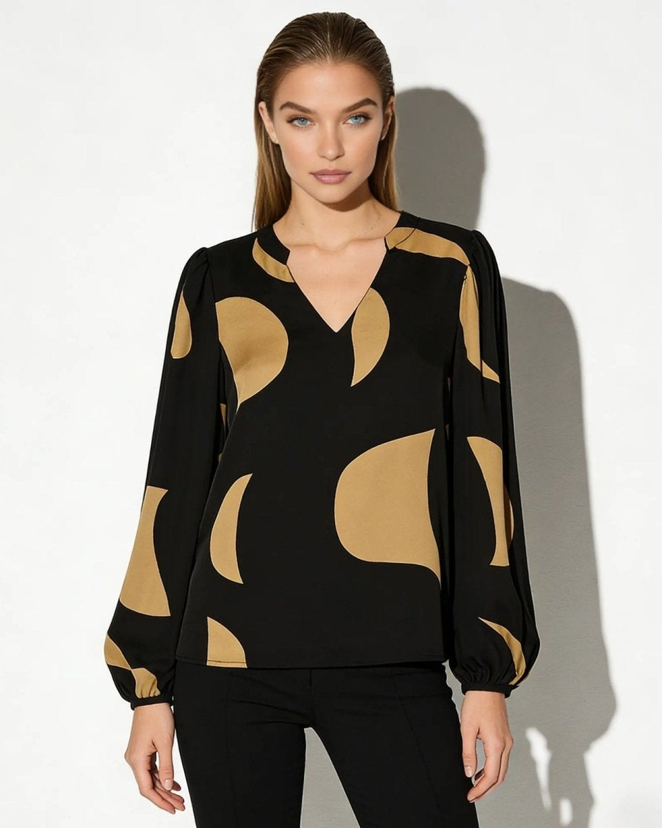 Model wearing the Judith black and tan abstract print blouse with long bishop sleeves and a V-neck, paired with black trousers.