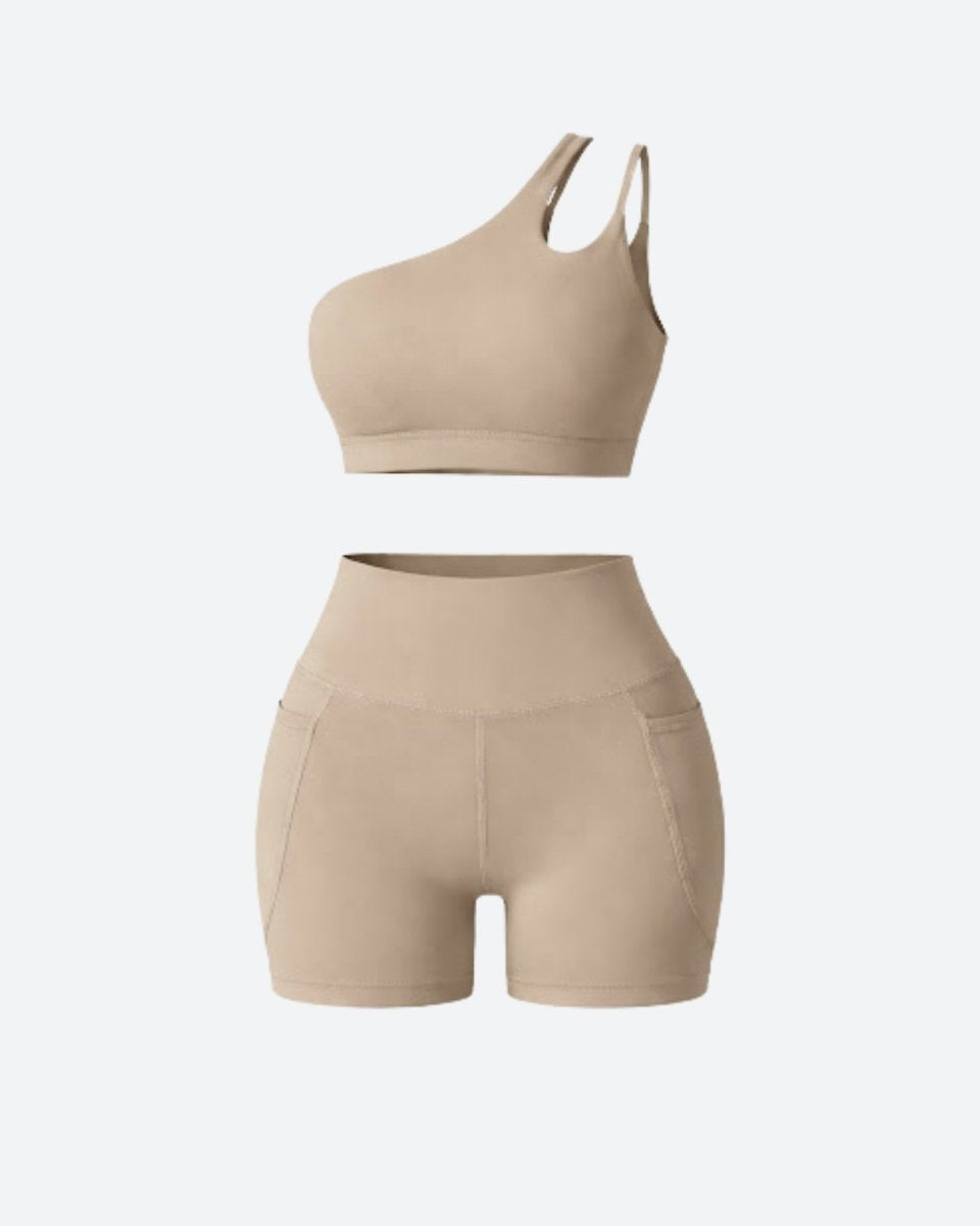 Flat lay clothing studio view of khaki asymmetrical sports bra with strap cutout and high waisted pocket biker shorts.