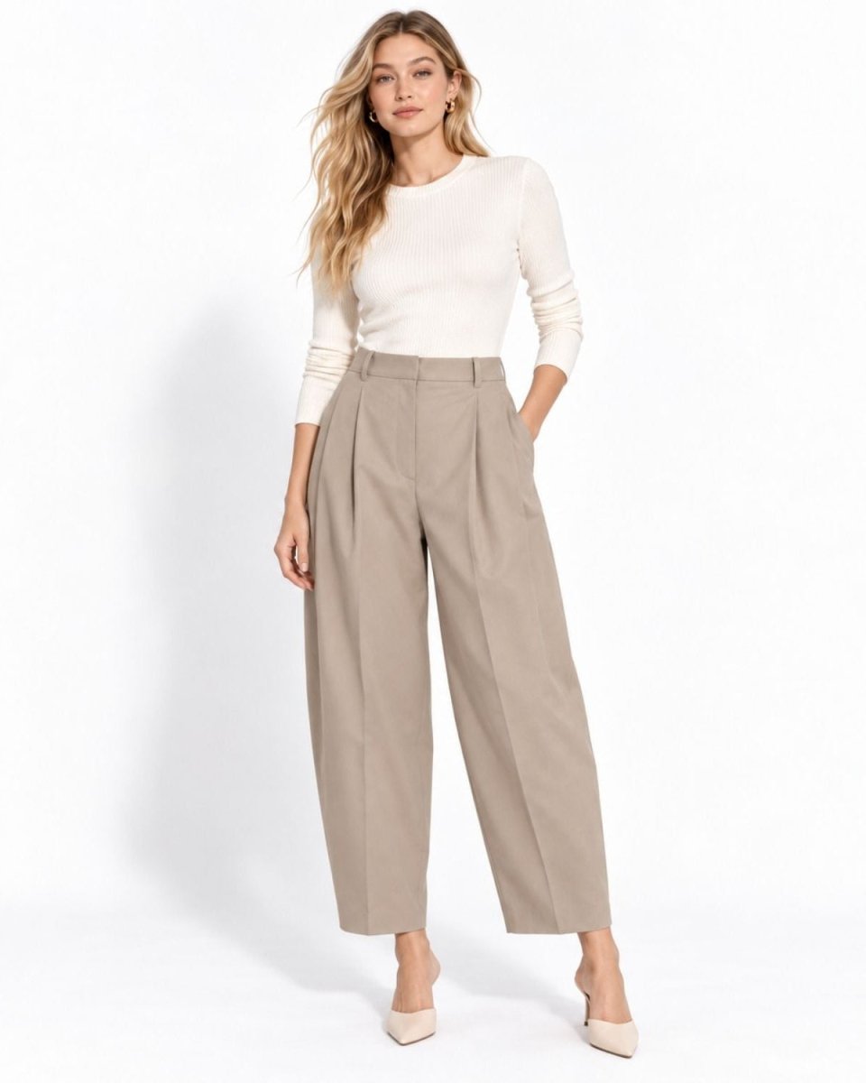 Front view of women's high waisted pleated barrel leg trousers in taupe beige, styled with a white long sleeve top and nude heels.