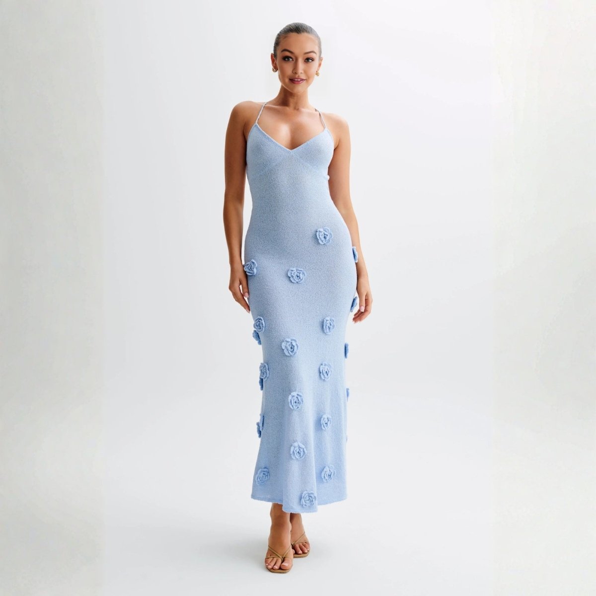 Woman wearing a light blue dress with floral embellishments on a white background