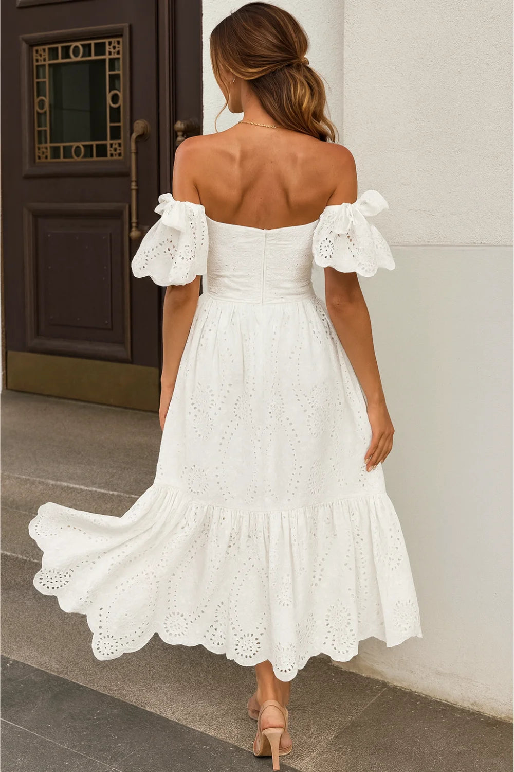 Model wearing the Kouvr Annie white eyelet midi dress on a balcony overlooking the ocean