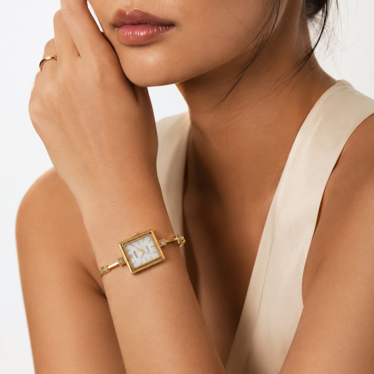 Elegant woman wearing dainty gold square dial bracelet watch by Kouvr showing scale and sophisticated styling