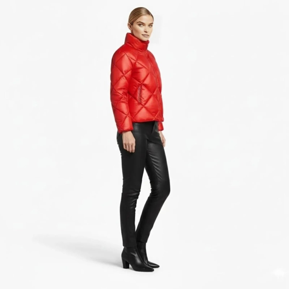 Side profile of a woman in a short red puffer jacket showing its hip-length fit and quilted texture.
