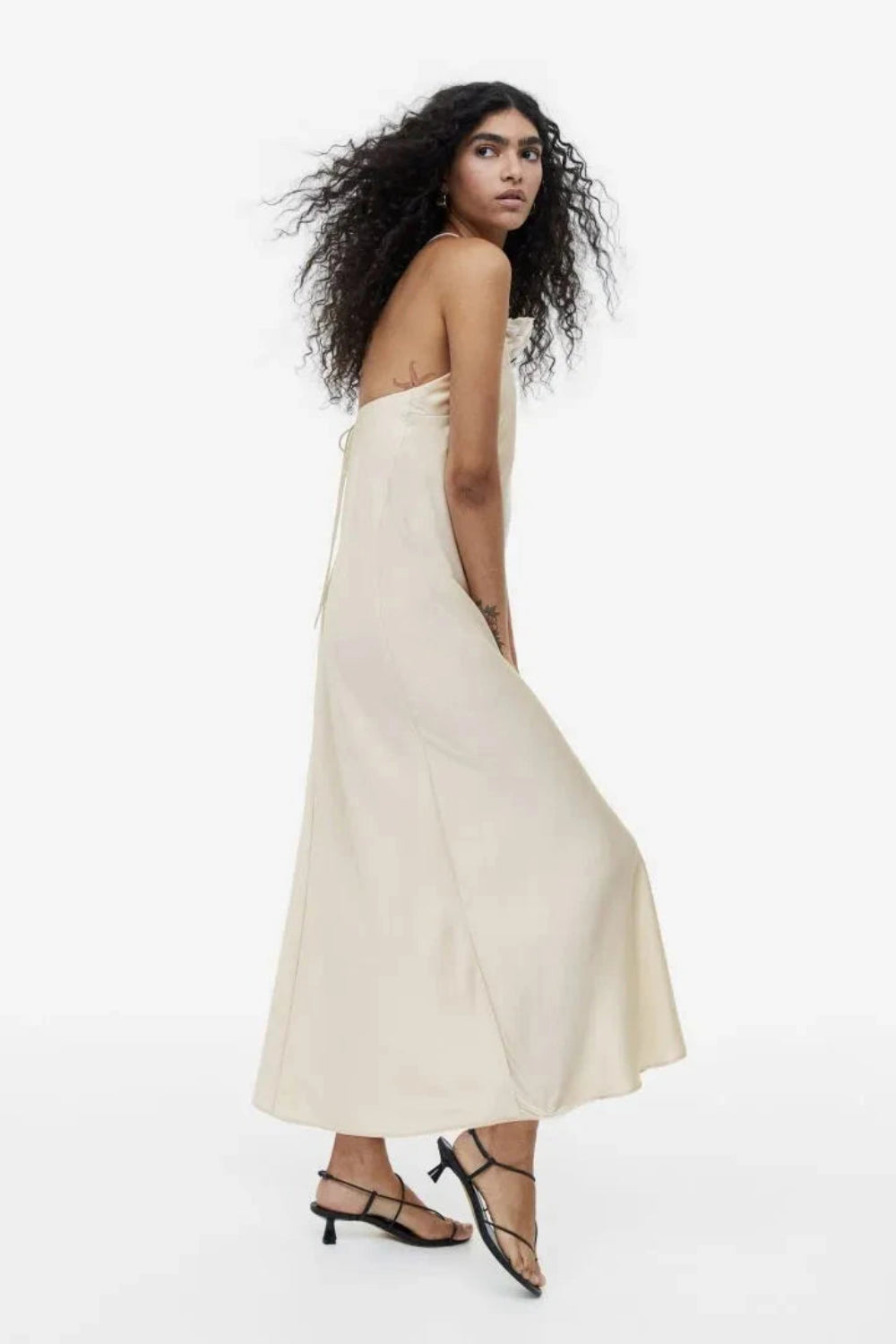 Model from behind wearing the Kouvr Fashion Cathalina beige satin halter dress showing the open back and criss-cross straps