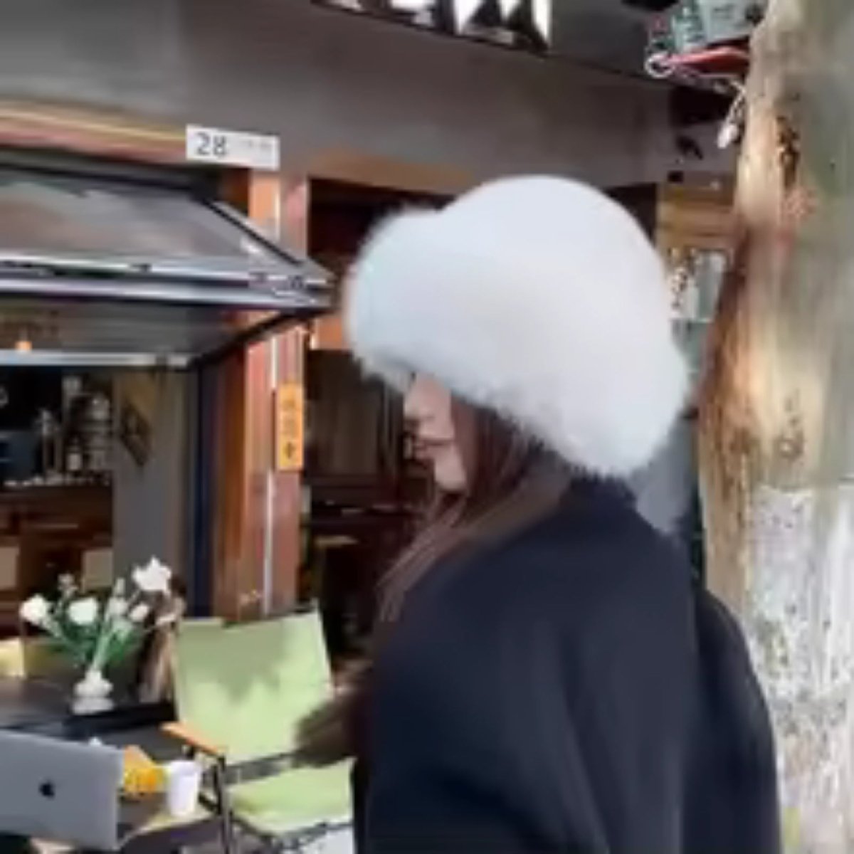 Person wearing a white fur hat in an indoor setting with furniture and decor.