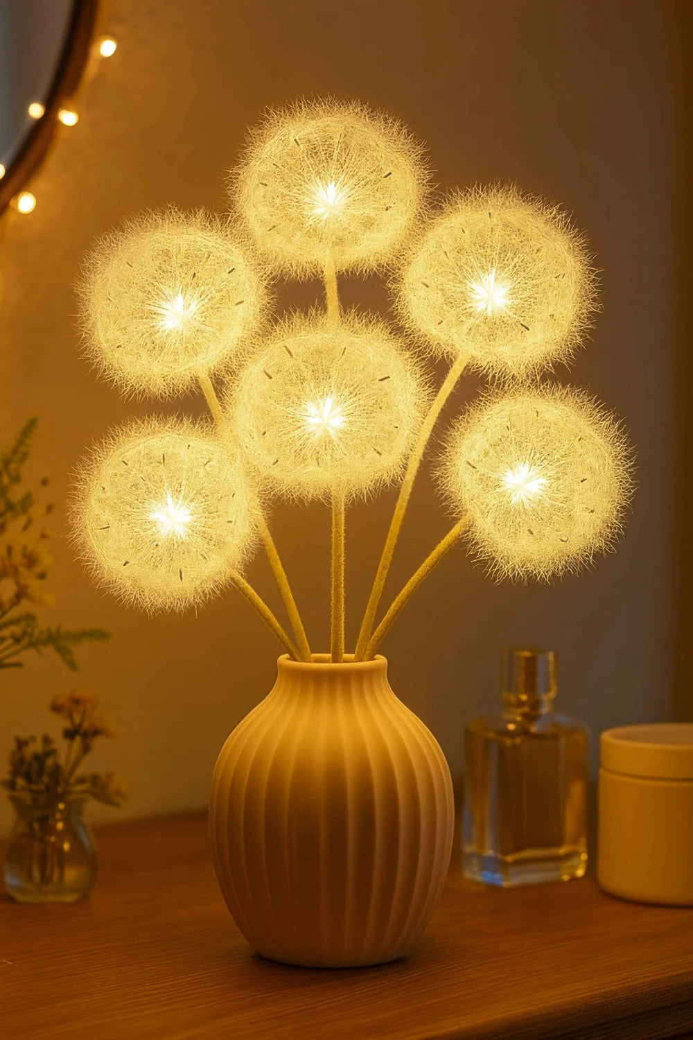 Close-up of the Kouvr Floral Accent Lamp, showing the detailed, glowing dandelion heads in a white ceramic vase on a dining table.
