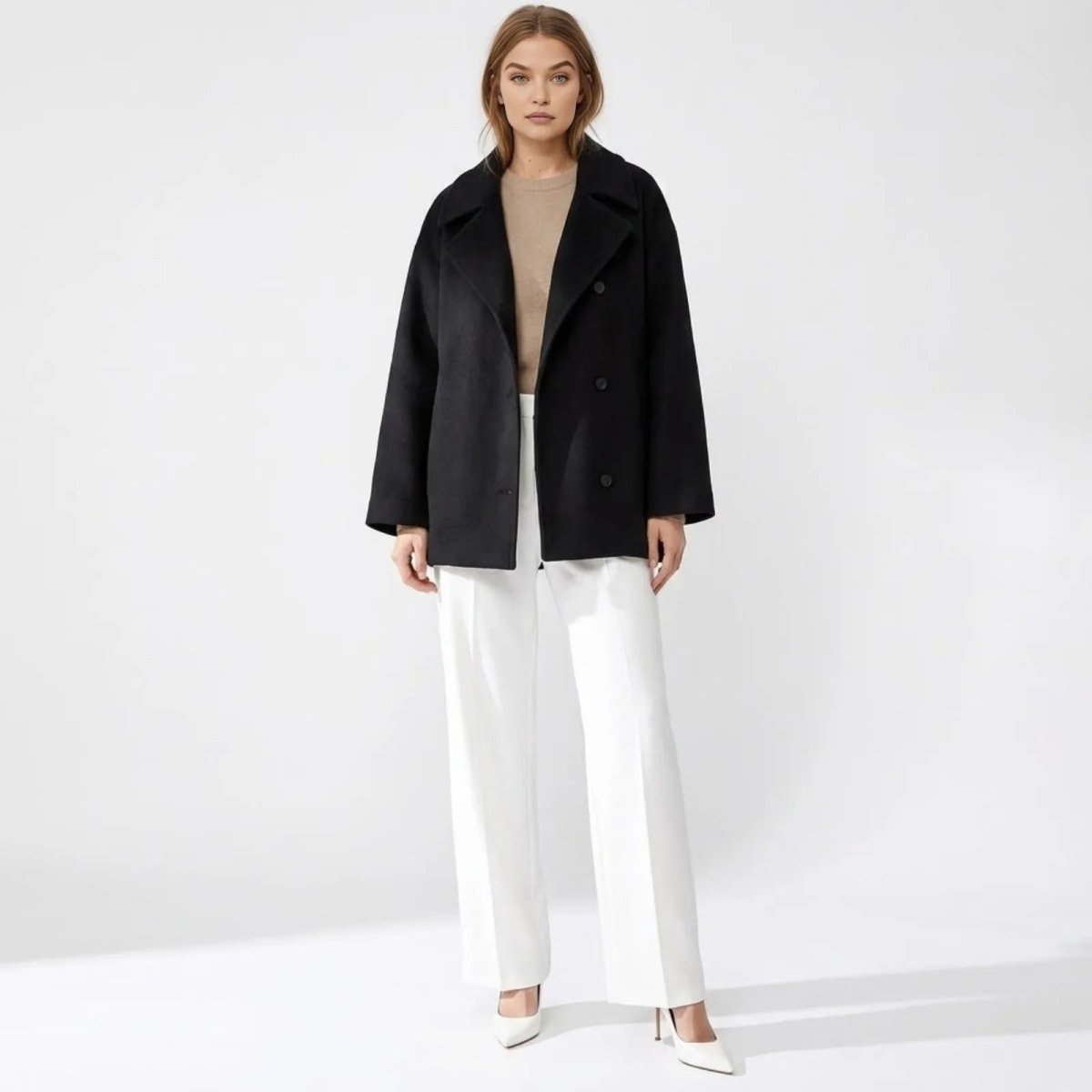 Model wearing the Kouvr Fashion oversized double-breasted black wool peacoat with white wide-leg trousers and heels.
