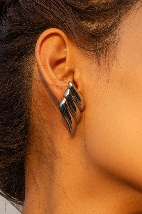 A detailed close-up shot of the Kouvr Fashion silver architectural statement earrings on a model's ear, highlighting the ribbed texture.