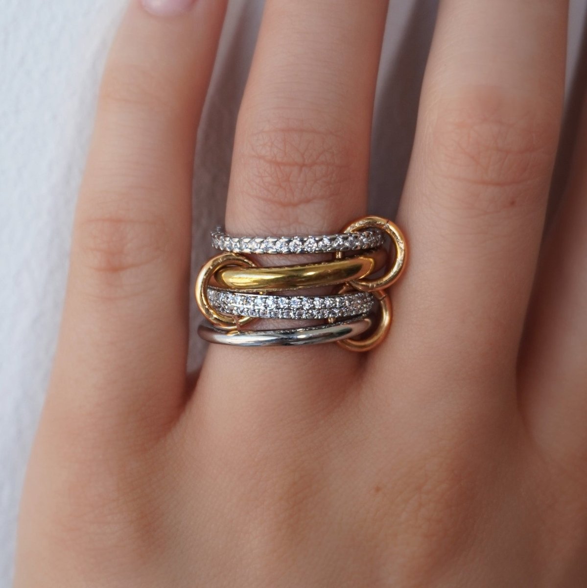 The Kouvr Lirien 18K mixed metal interlocking ring with pavé diamond bands worn on a finger.
