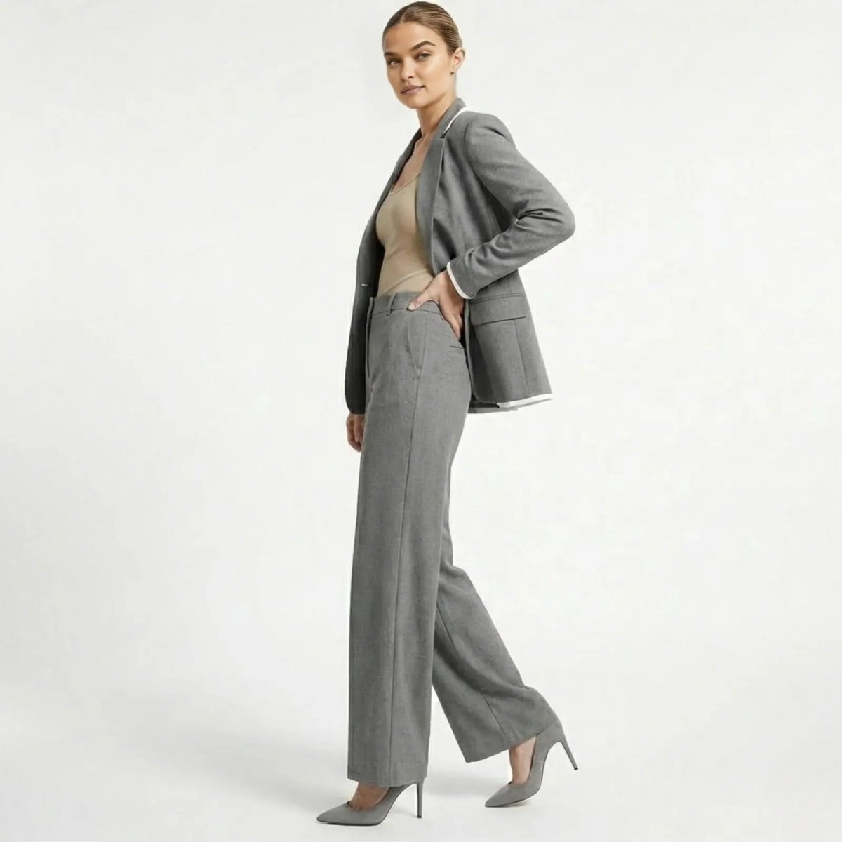 Model in a side profile view showcasing the fluid drape of the Kouvr Lucia Set grey wide-leg pantsuit and the tailored fit of the blazer.
