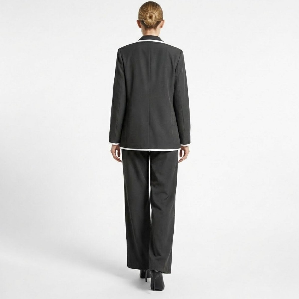 Back view of the Kouvr Lucia Set dark grey blazer and trouser set, showing the clean lines, center vent on the blazer, and full-length wide-leg pants.
