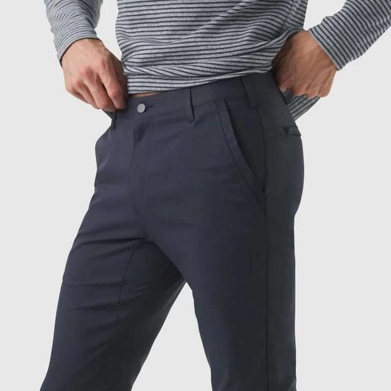 Close-up detail shot of the Kouvr All-Day Commuter Pant in navy, showing the technical fabric, front slash pocket, and button closure.