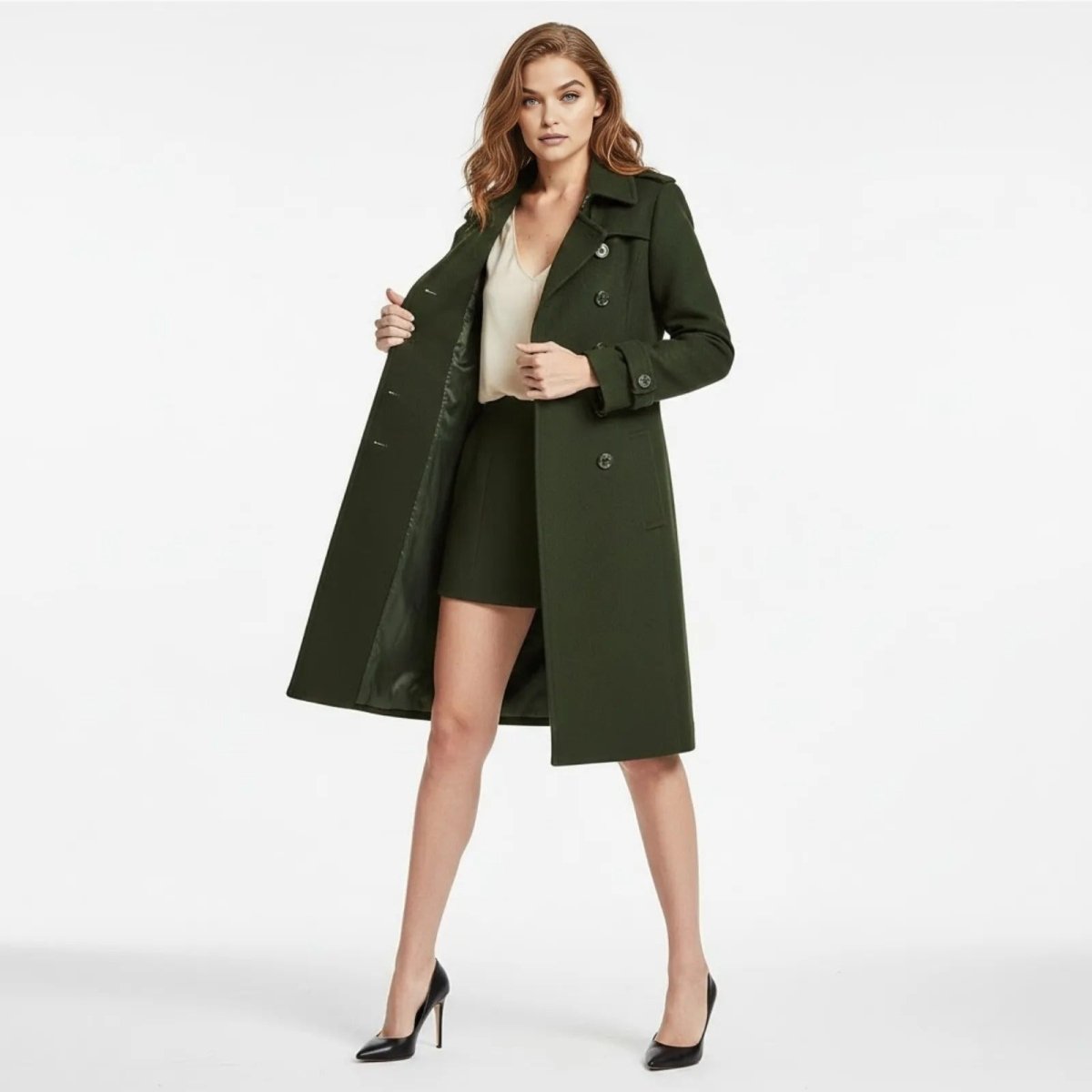Model wearing the Kouvr Rachelle women's double-breasted wool trench coat in army green, styled open over a cream top and matching green skirt.
