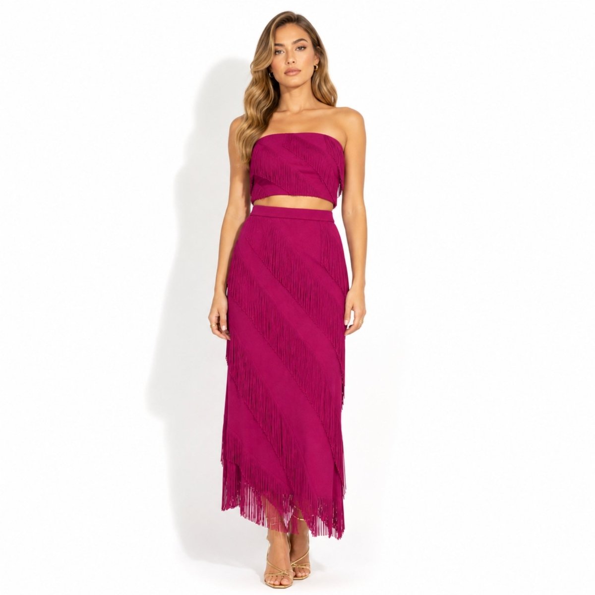 Full length front view of vibrant magenta pink tiered fringe statement skirt styled with matching crop top