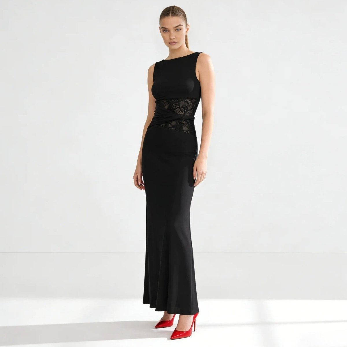 Model wearing the Kouvr sleeveless black midi dress, showcasing the asymmetrical sculpted waist detail and elegant bodycon silhouette against a white background. 