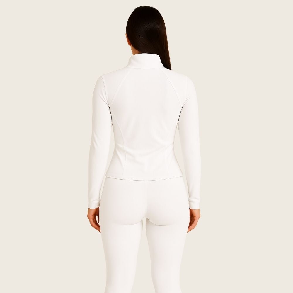 Model wearing the white Kouvr Sculpting Athletic Jacket in a modern fitness studio.