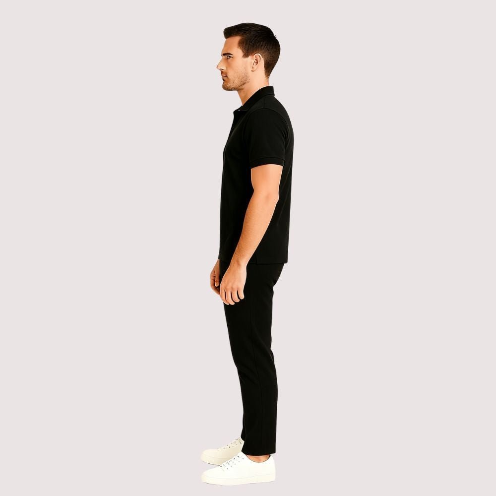 Man wearing a black kouvr polo shirt and pants on a light gray background