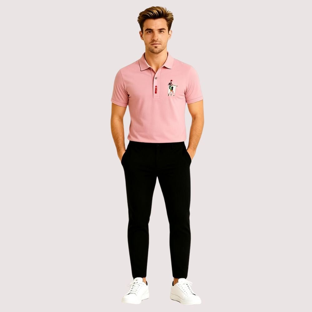 Man wearing a pink kouvr polo shirt with a logo and black pants on a light gray background