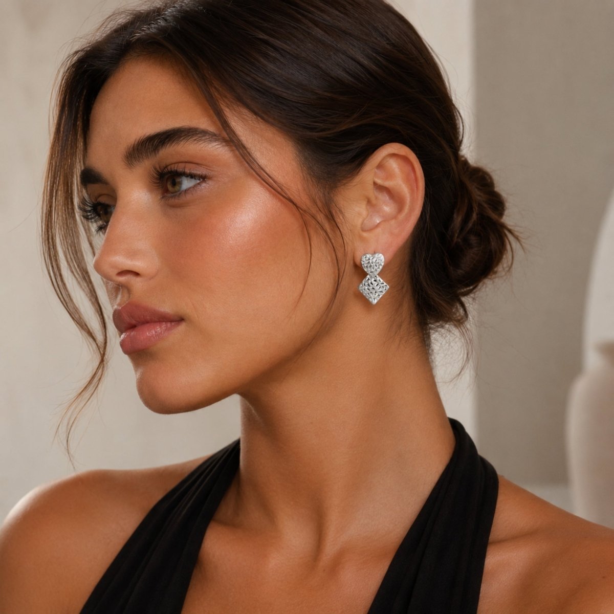 Sophisticated model in black halter dress wearing Kouvr textured silver heart geometric dangle statement earrings