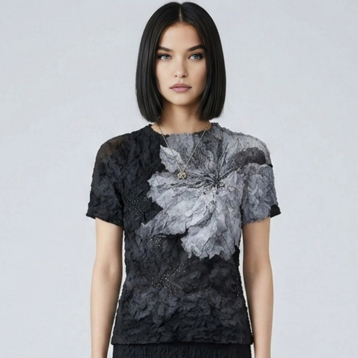  Woman modeling the Kouvr black and grey textured short sleeve top featuring an oversized floral design.