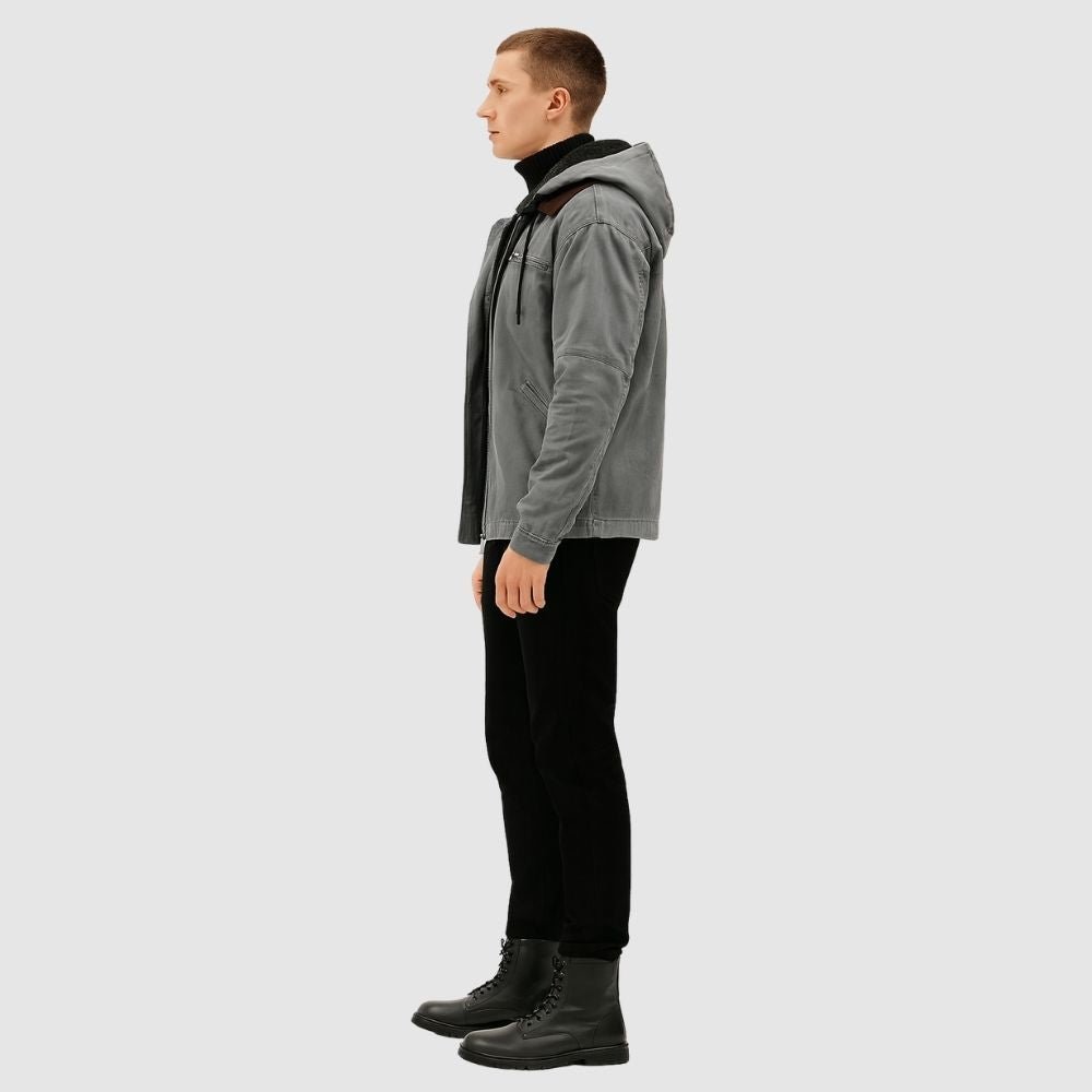 Man wearing the Kouvr tyrian sherpa-lined gray canvas hooded jacket, facing side with hands in pockets.