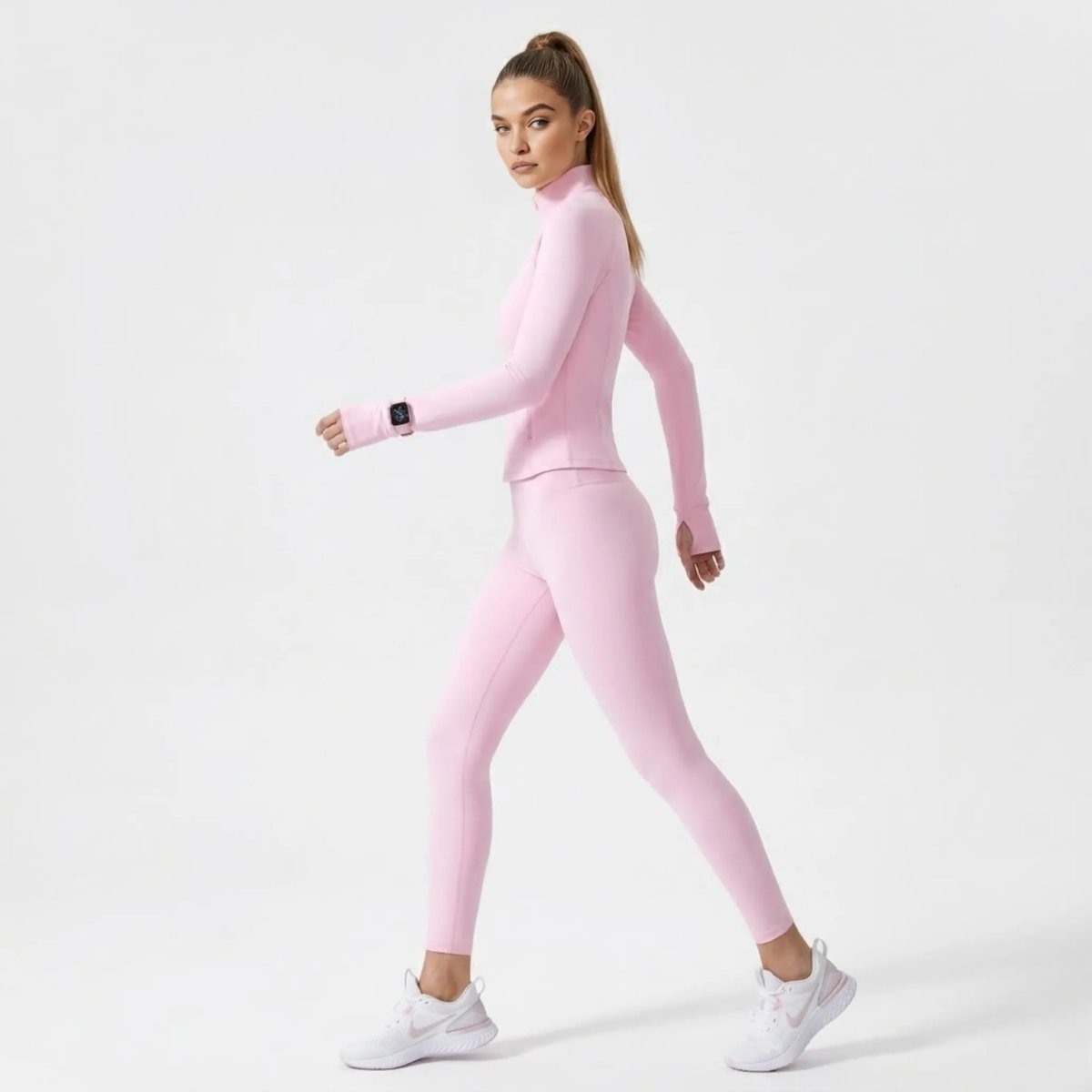 Side profile of woman walking confidently in Kouvr  pink workout jacket highlighting functional thumbholes and a sculpted silhouette.