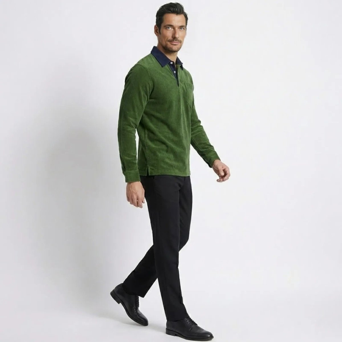 Side profile of a man walking in a green corduroy polo shirt and black pants.
