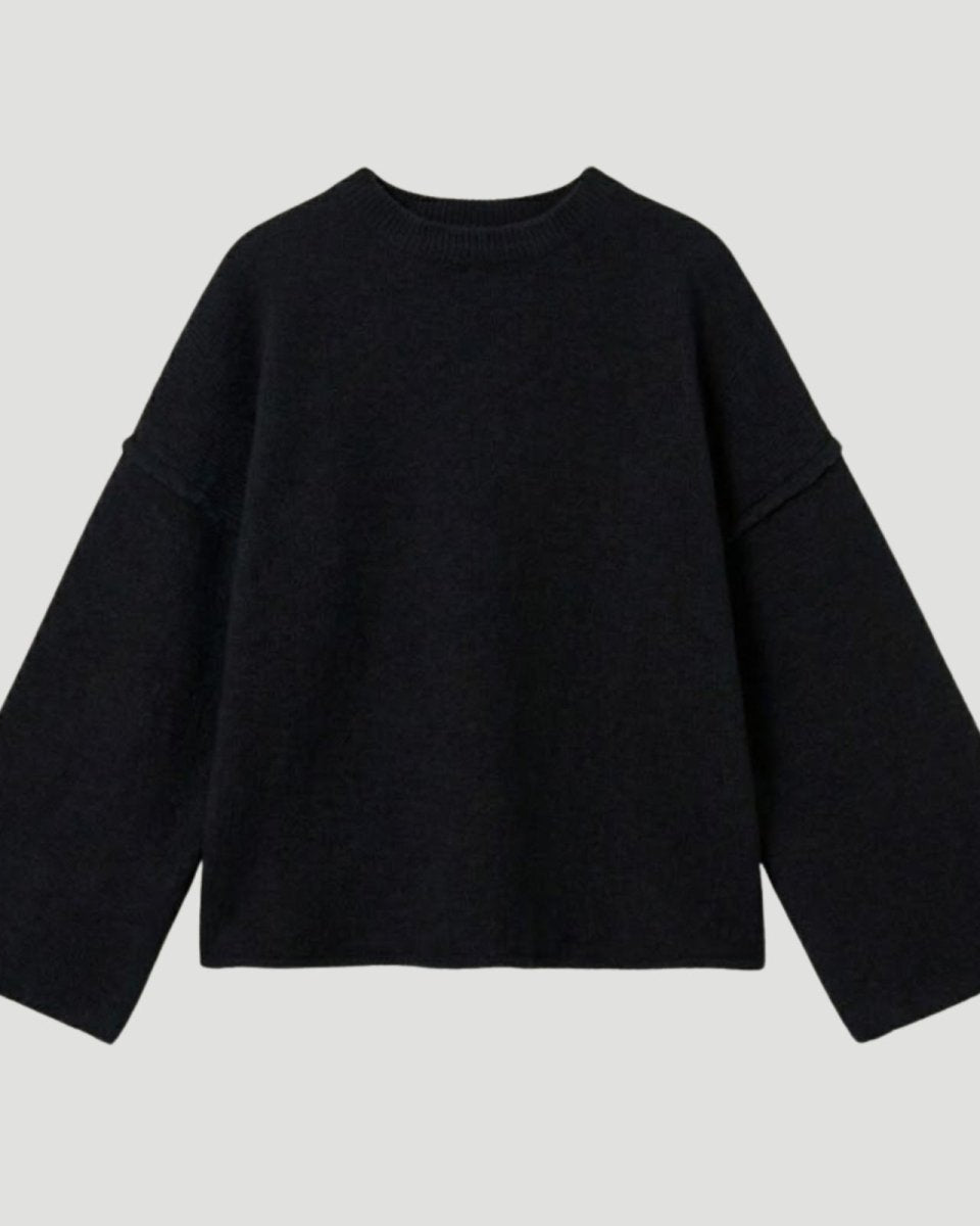 Flat lay of a black oversized crewneck sweater with wide bell sleeves and external seam details, made from a luxury wool-cashmere blend.