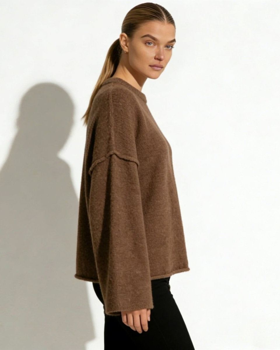 Side profile of the brown alpaca blend sweater showcasing the dramatic width of the bell sleeve and the dropped shoulder seam detail.