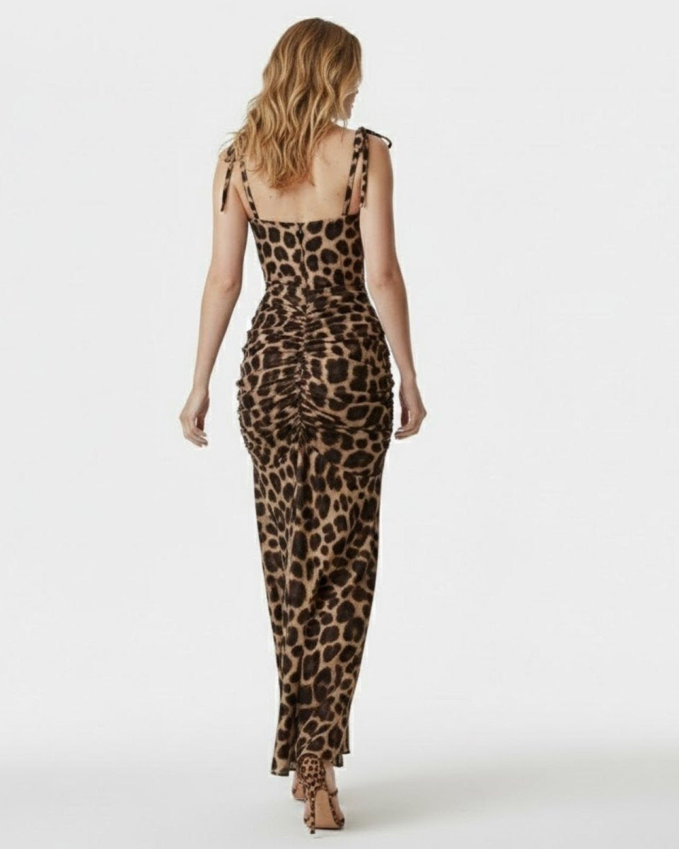 Back view of a model in a leopard print bodycon maxi dress, highlighting the ruched detailing on the seat and adjustable tie-shoulder straps.