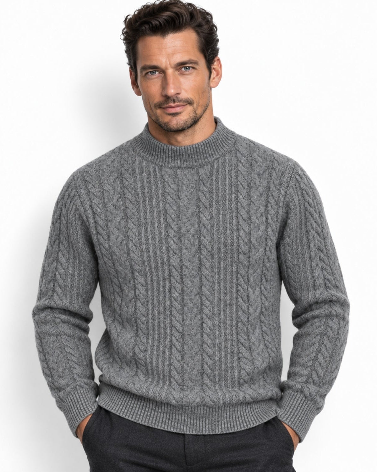 A man wearing a gray cable-knit mock neck sweater, standing against a plain white background.