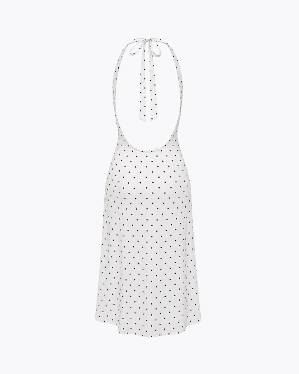 Flat lay back view of an open back halter tie polka dot dress emphasizing the adjustable neck ties and low back cut.