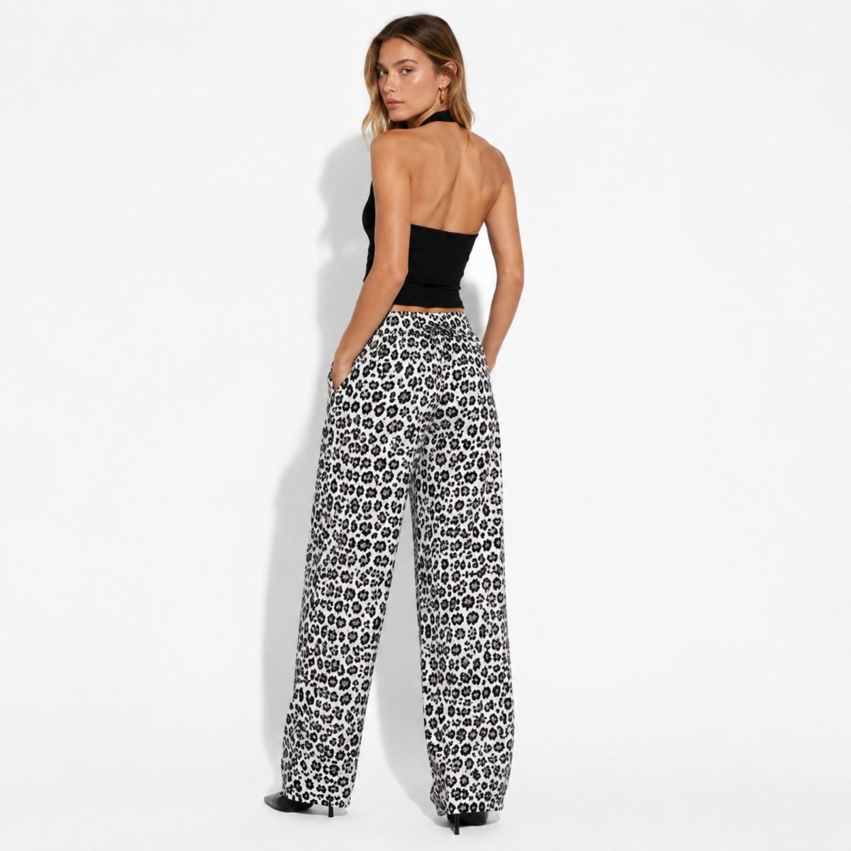 Back view of model wearing luxury women's leopard print trousers highlighting the flattering rear drape and elastic waistband