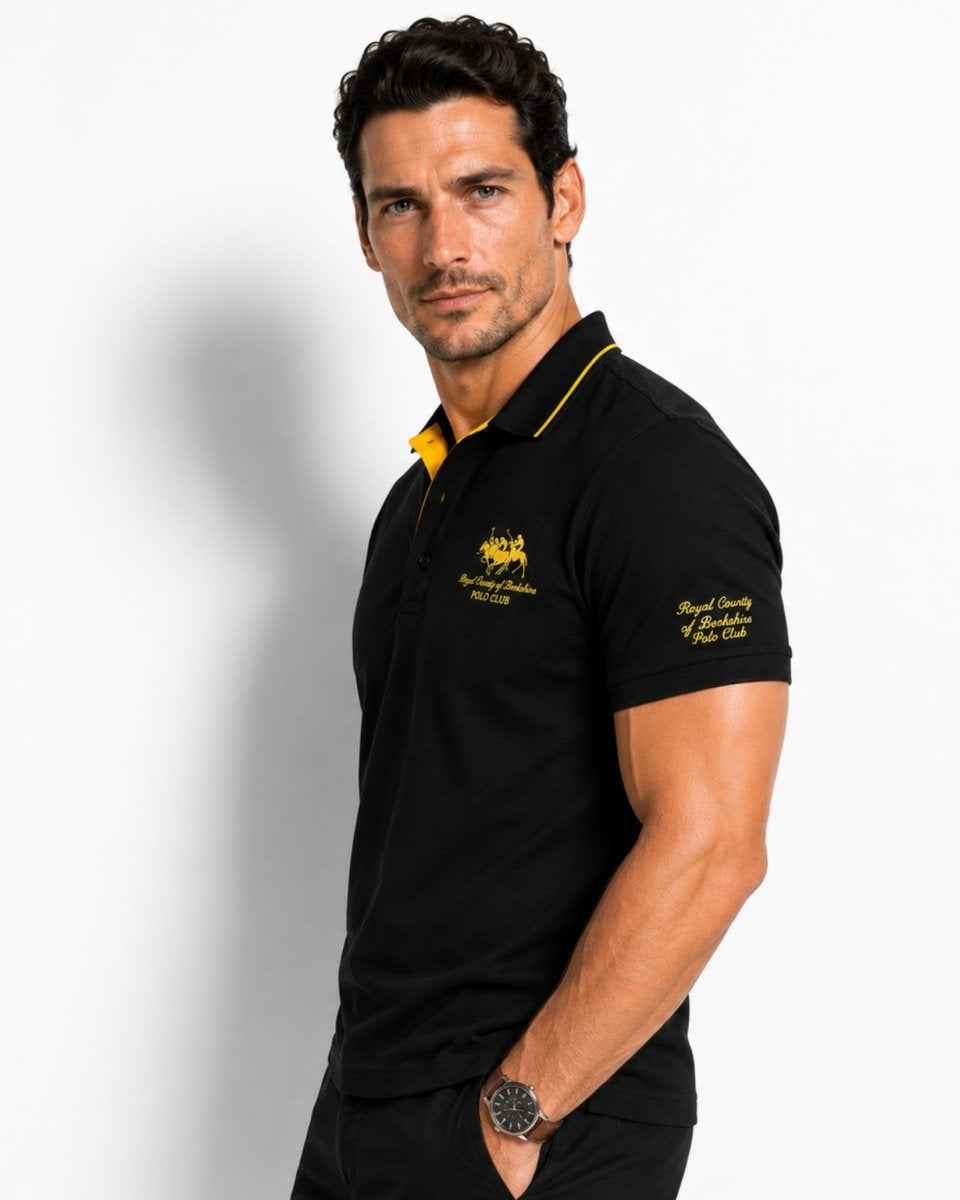 Man wearing a black polo shirt with yellow accents on a white background