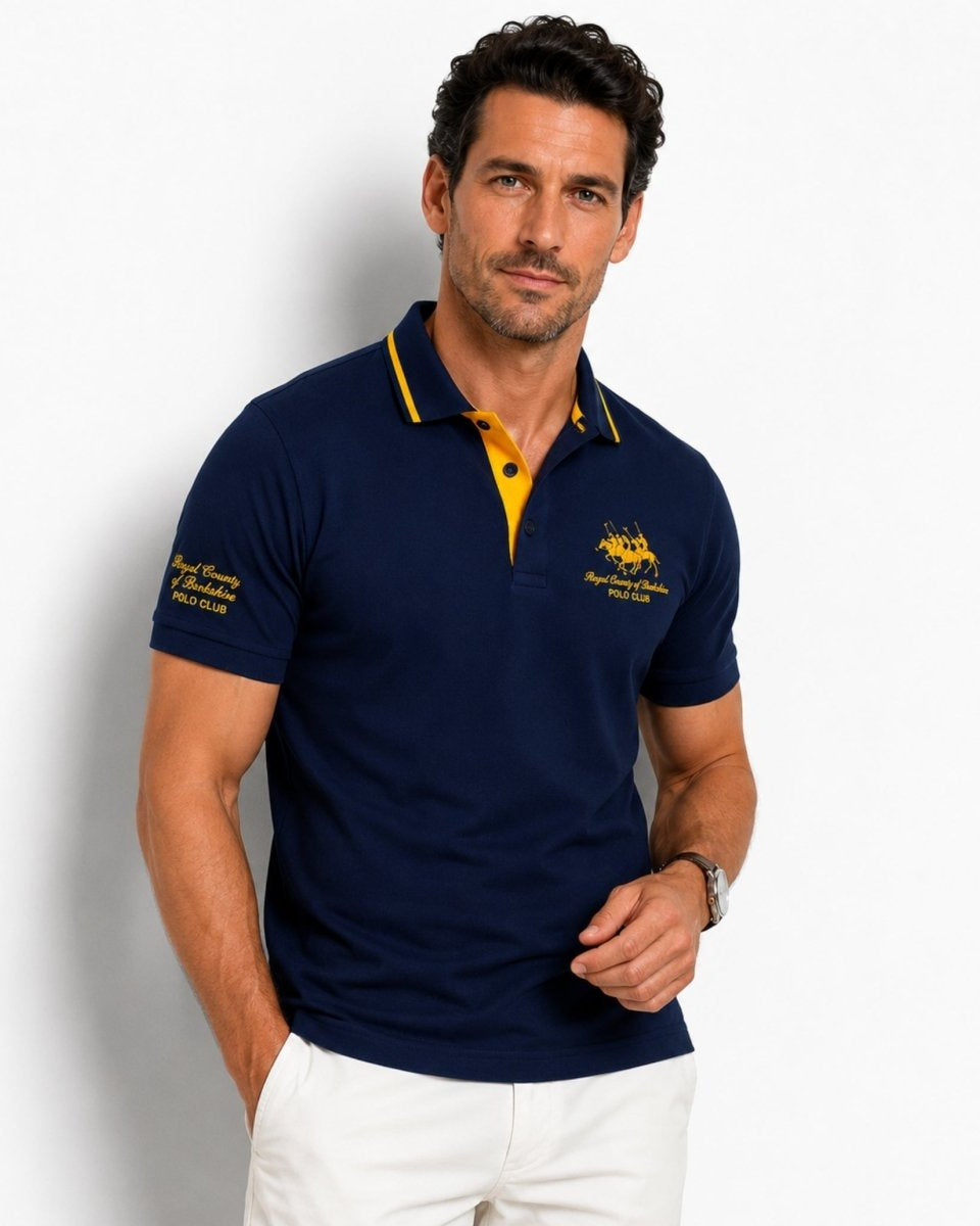 Man wearing a navy blue polo shirt with yellow accents on a white background